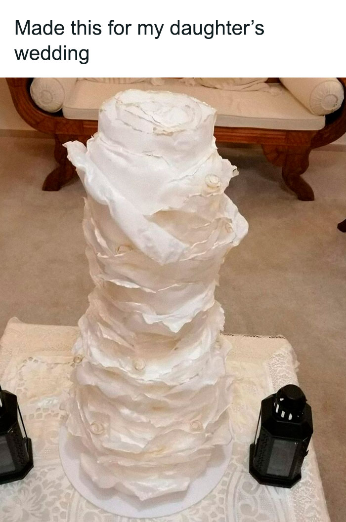 Tall, uneven wedding cake with rough edges on a table, showcasing a funny baking fail.