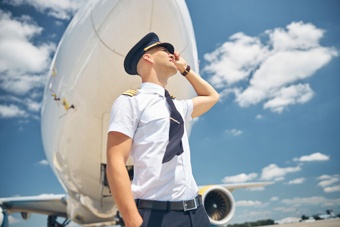 Pilot in uniform standing confidently in front of a plane, representing life after a "useless" degree.
