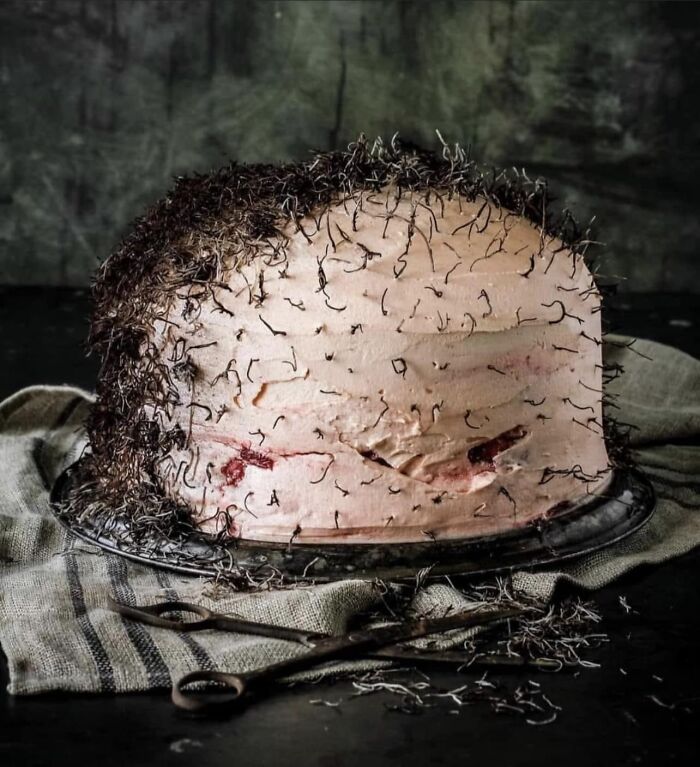 Unusual cake design with hair-like frosting, resembling a humorous baking fail, set against a dark backdrop.