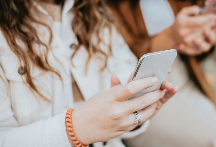 Person using a smartphone, reflecting on skipping friend's wedding. Person using a smartphone, reflecting on skipping friend's wedding.