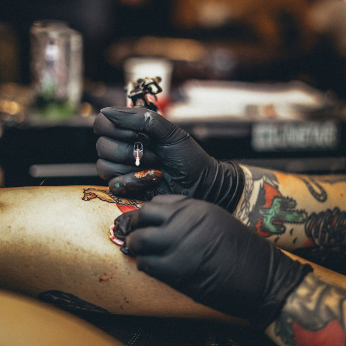 Tattoo artist inking a colorful design on a client's arm in a studio session.
