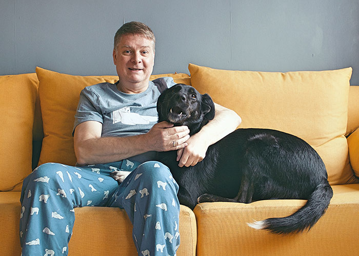 Man relaxing on a yellow couch with a black dog, resembling memorable dad stories.
