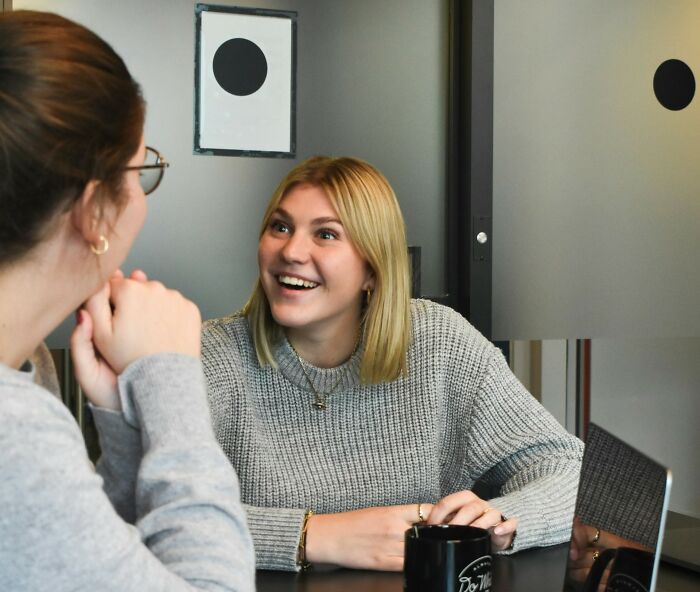 Two women in a positive job interview, one smiling, at a table with a coffee mug.