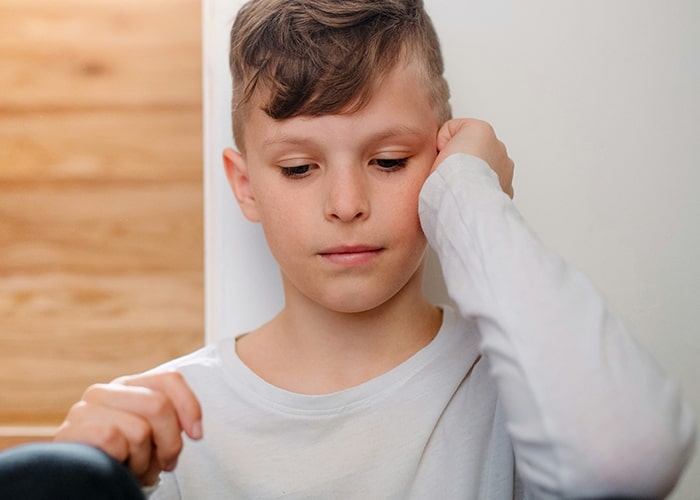 Child in a white shirt, looking thoughtful, related to parenting mistakes.