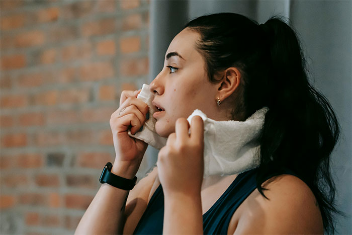Woman looking thoughtful, holding a towel to her face, concerned about smelling after not showering for days. Woman looking thoughtful, holding a towel to her face, concerned about smelling after not showering for days.