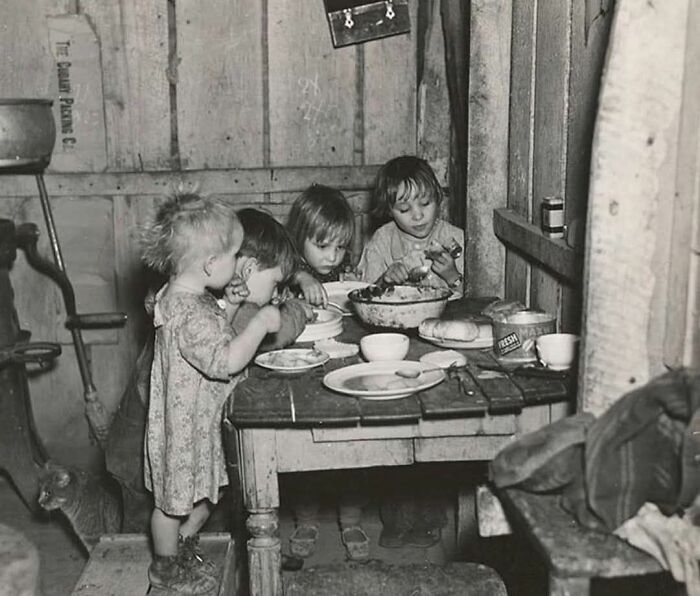 Children sharing a meal around a rustic wooden table, capturing a lesser-known historical moment.