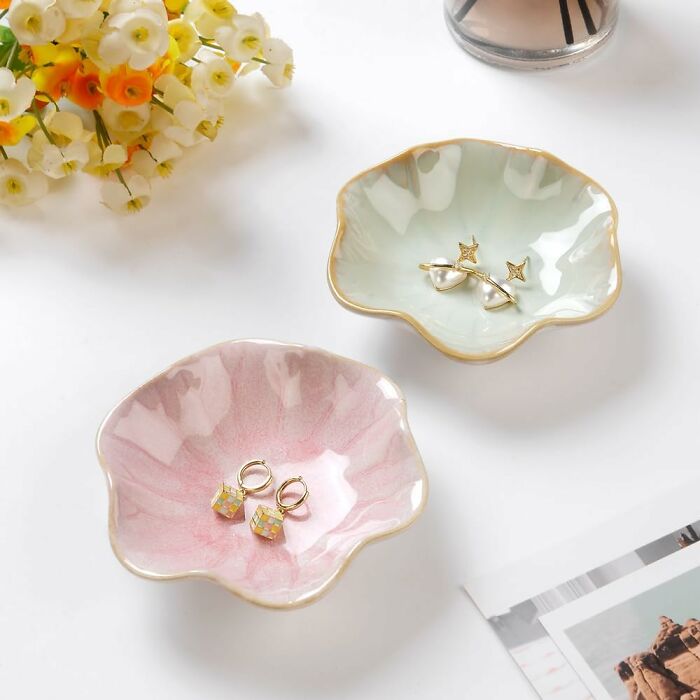Elegant spring finds: pastel jewelry dishes with gold trim, adorned with earrings, beside delicate flowers.