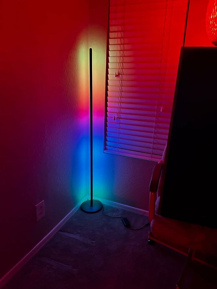 Colorful LED floor lamp in a dim room, casting vibrant rainbow hues on the wall.