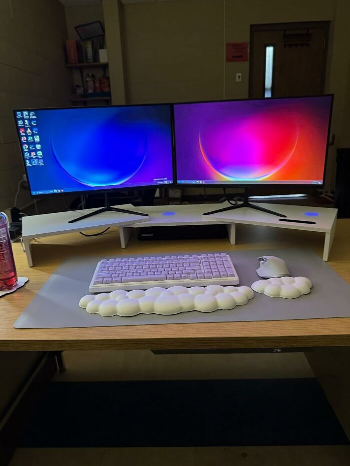Dual monitors on a desk with a keyboard and ergonomic wrist pad, capturing the essence of office Olympics workspace setup.