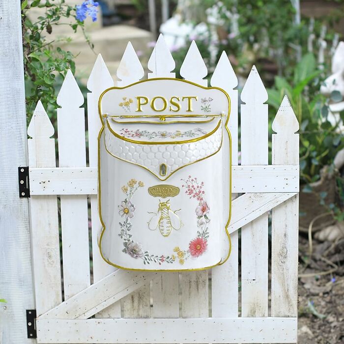 Spring finds: Floral mailbox decor on a white picket fence in a garden setting.
