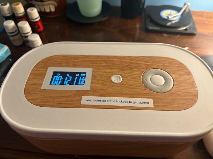Wooden lockbox timer for digital detox on a desk with essential oils in the background.