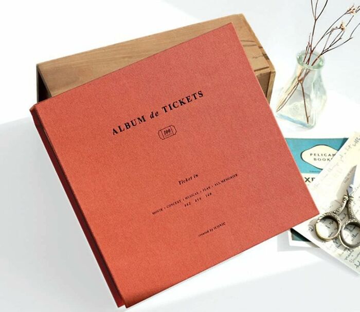 Ticket album displayed on a table with a wooden box, showcasing a stylish way to honor keepsakes.