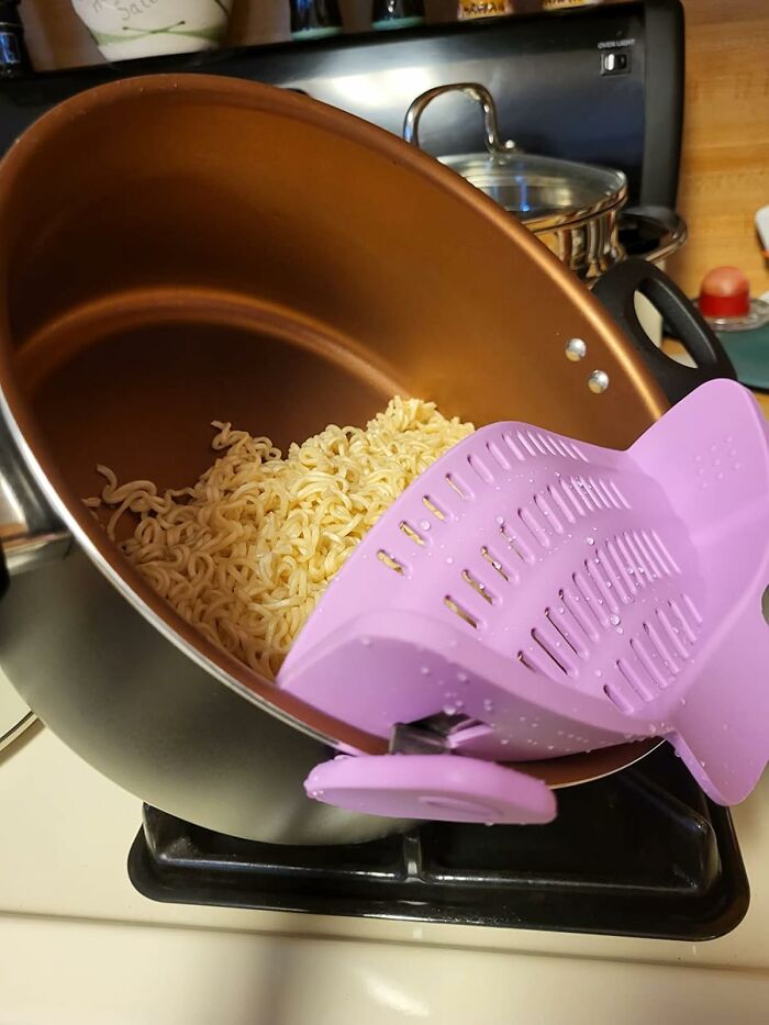 Pot with noodles and a pink clip-on strainer, a kitchen game-changer.