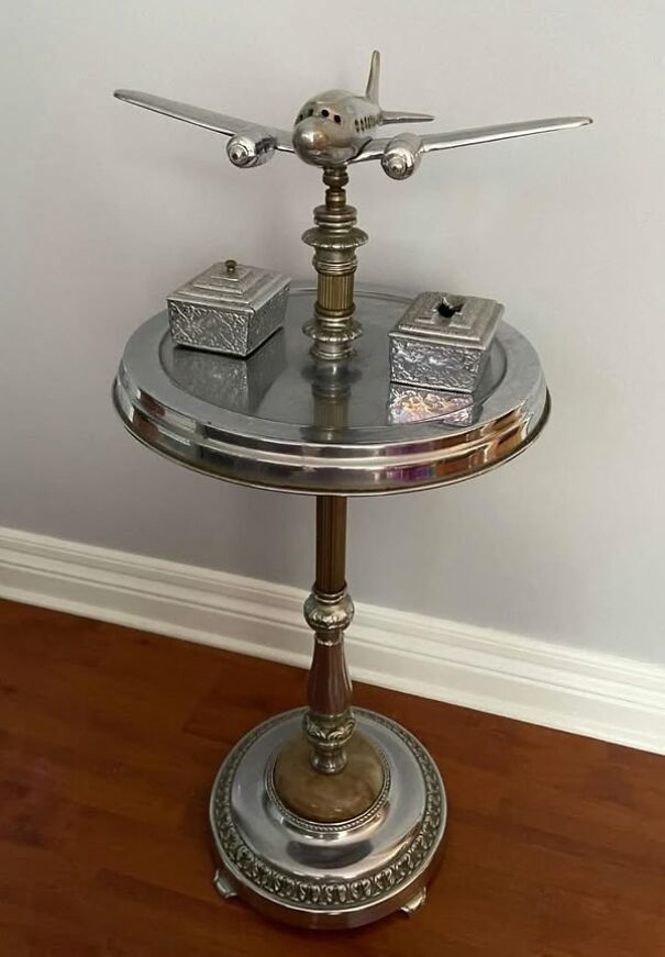 Thrifted item: Airplane-shaped metal decorative piece on vintage pedestal table in a corner setting.