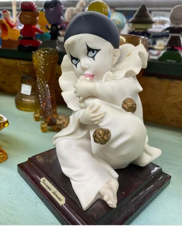 Porcelain clown figurine with tearful eyes, found while thrifting, displayed on a green table.