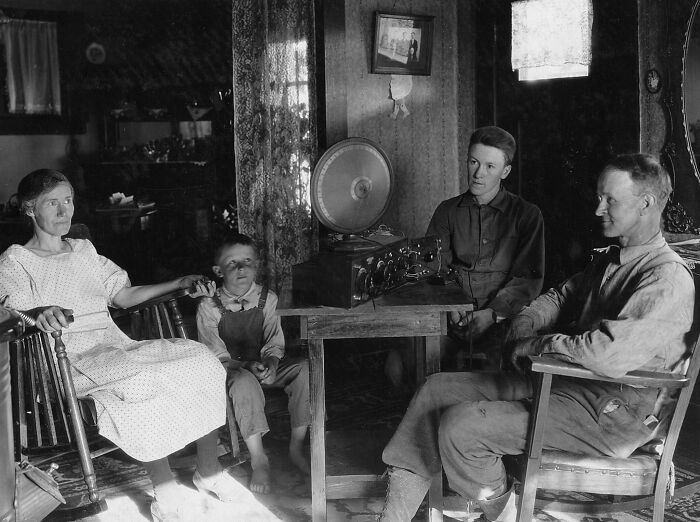 A family from 50-100 years ago gathered around an early radio, illustrating how much the world has changed.
