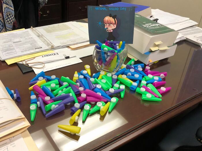 Colorful kazoos scattered on an office desk, featuring a "National Kazoo Day" card, illustrating a playful Amazon product review.