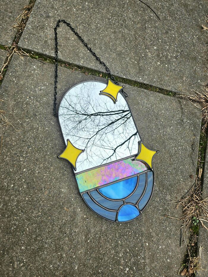 Unique DIY stained glass project with mirror and colorful accents laying on pavement.