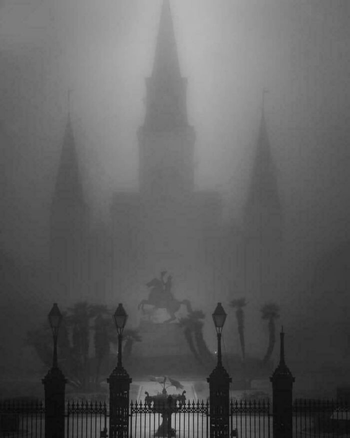 Gothic building with spires and a statue, shrouded in thick fog, giving an evil aura like a supervillain headquarters.
