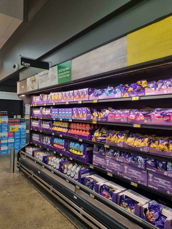 Australian grocery aisle with shelves full of chocolate eggs and treats under an eggs sign.