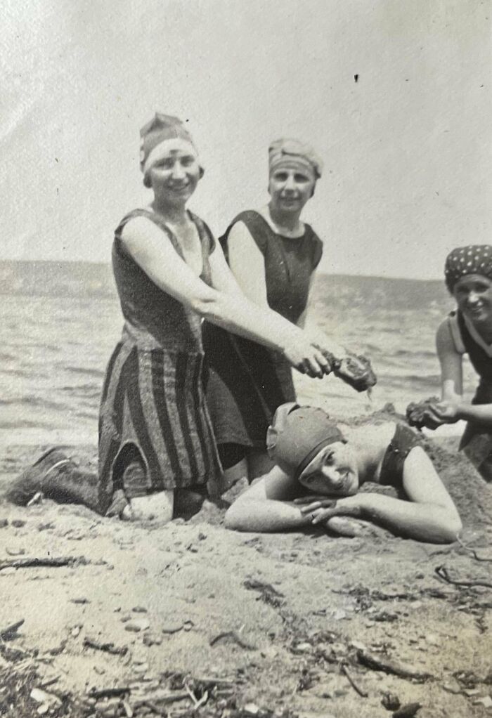 Four women in vintage swimwear enjoying a candid moment on the beach in historical photographs.