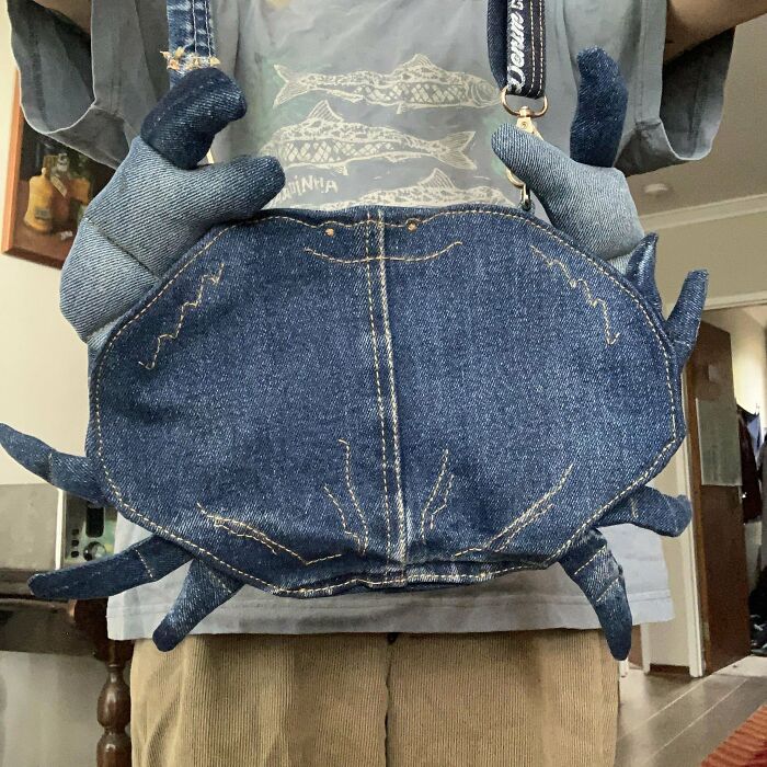DIY project featuring a denim bag designed to resemble a crab, held by a person wearing gloves.