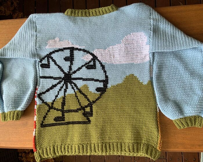 Crochet sweater with Ferris wheel and clouds design in blue and green yarn, showcasing incredible crochet craftsmanship.