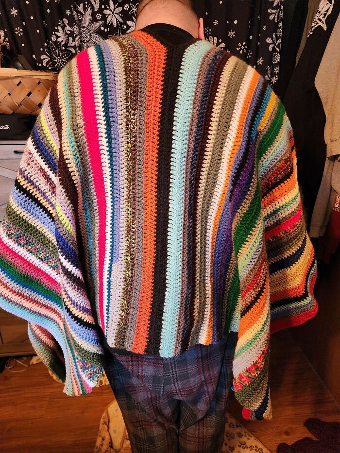 Person wearing a colorful striped crochet shawl showcasing incredible craftsmanship by crochet enthusiasts.