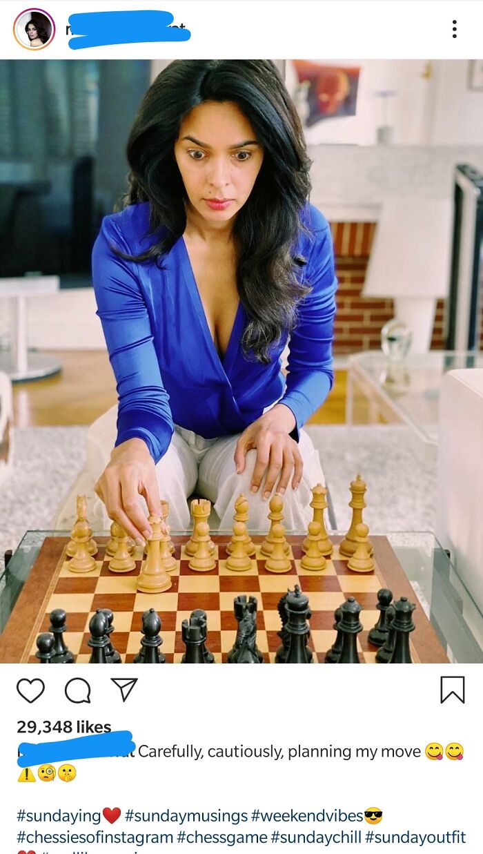 Influencer in a blue top playing chess, intensely focused on her next move.