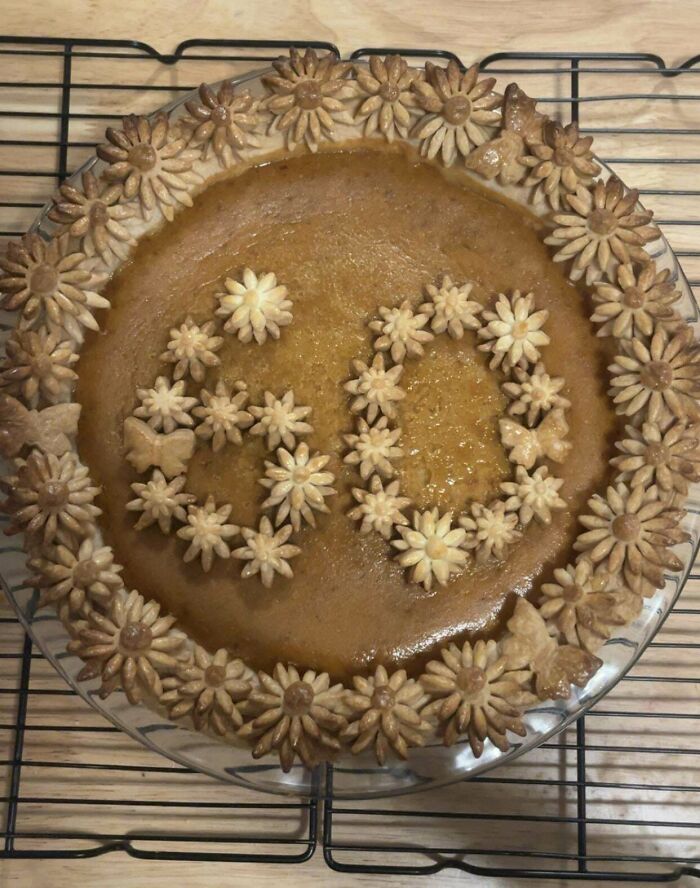 A beautifully decorated baked pie with intricate floral and butterfly crust designs showcasing incredible bakes.