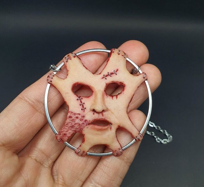 Creepy handmade craft featuring a stitched face design held by a hand.