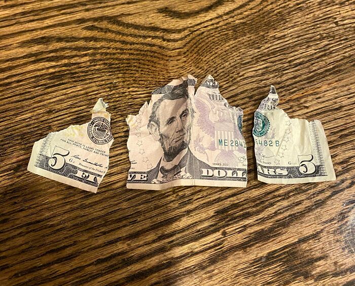 Torn five-dollar bill on wooden surface, representing mildly infuriating server tips experience.