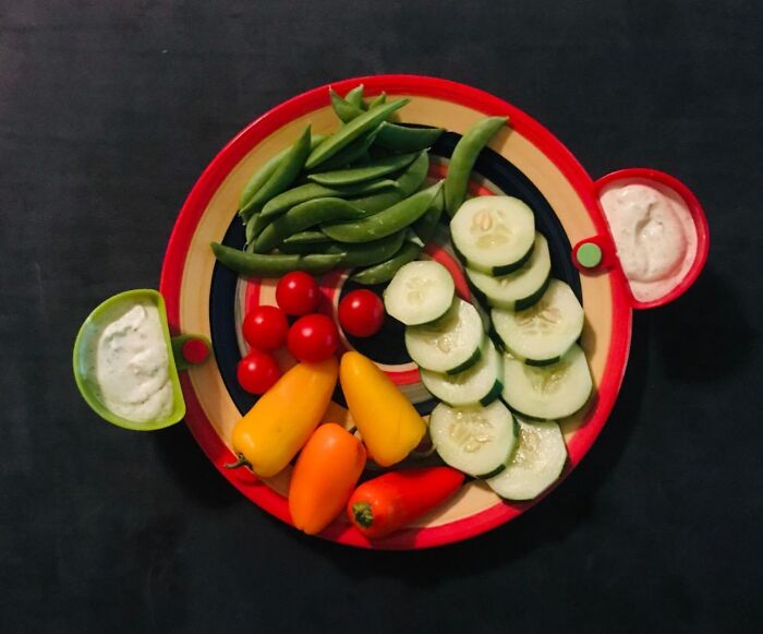 Colorful veggie platter with dip, including cucumbers, cherry tomatoes, snap peas, and mini peppers for cheap fixes.