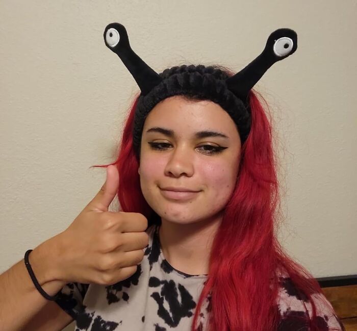 Person with red hair wearing fun antenna headband gives thumbs up, showcasing cheap fixes for life's problems.