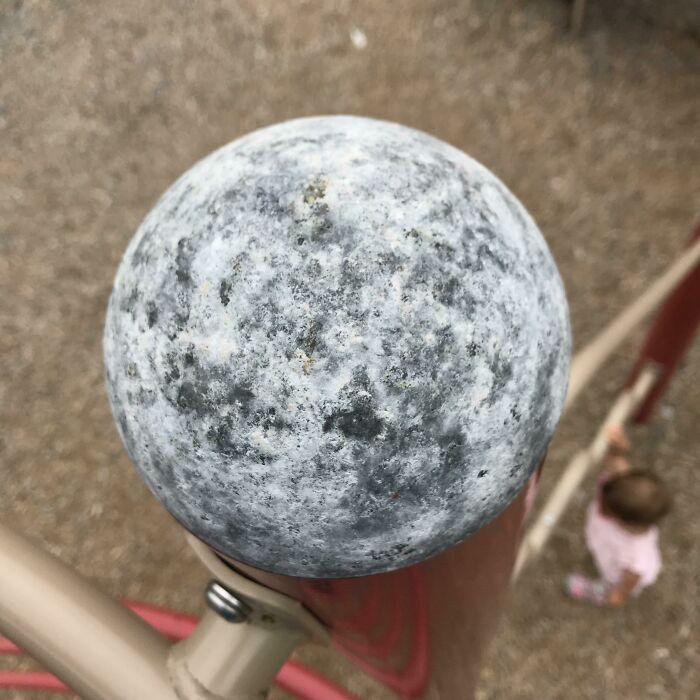 Worn playground dome shows signs of use over time, with a child playing in the background.
