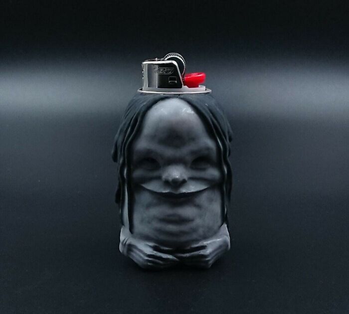 Creepy handmade craft resembling a small figure with dark hair, serving as a lighter holder.