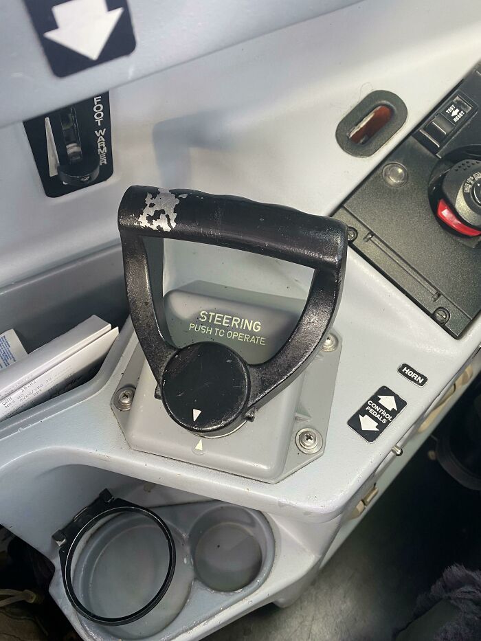Worn aircraft steering handle showing signs of use over time, with labeled controls for operating.