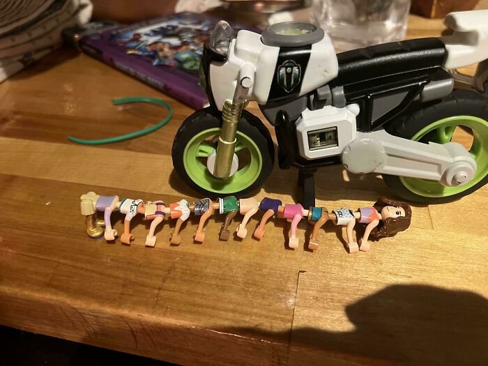 Juguetes extraños, muñecas LEGO formando una oruga frente a una moto. Imagen curiosa para arruinarte el día.