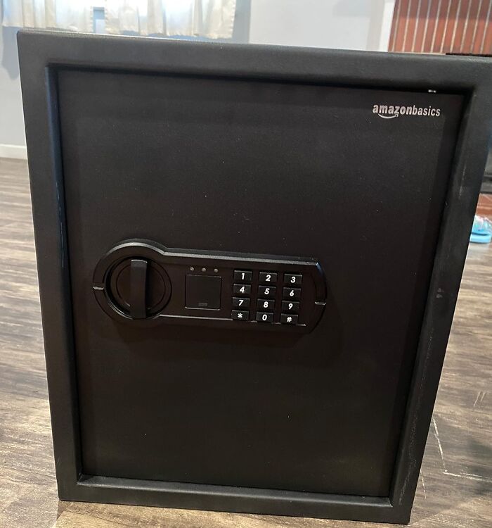 Safe for storing sentimental clutter, featuring a keypad and black finish, on a wooden floor.