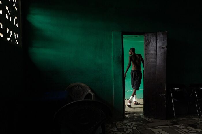 A man captured leaving a dark green room, demonstrating street photography by Andrea Torrei.