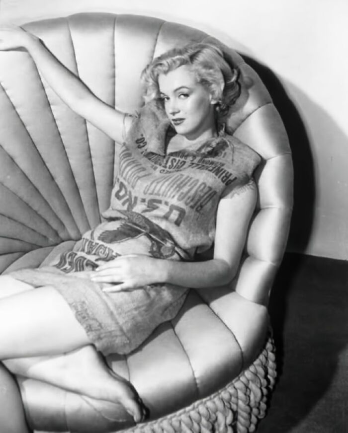 Woman lounging on a retro chair wearing a dress made from a sack, capturing vintage fashion resonating today.