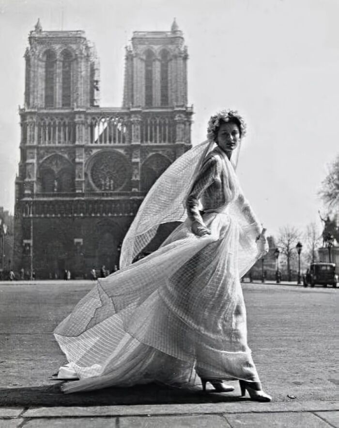 Woman in a flowing white dress in front of a historic cathedral, capturing timeless elegance over the years.