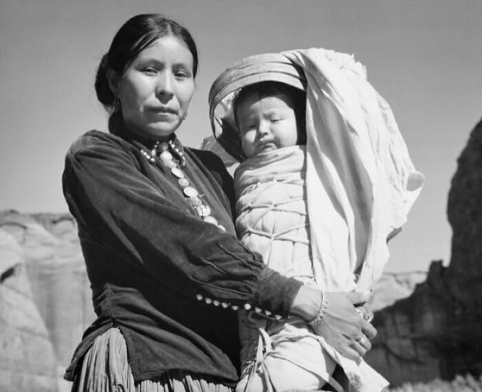 A woman from a hundred years ago holds a baby, capturing a timeless moment.