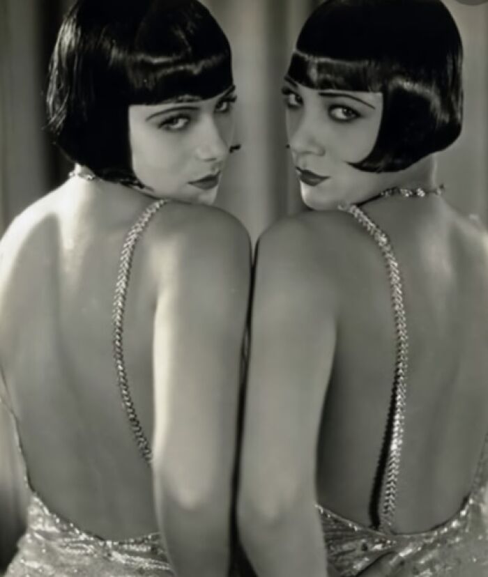 Two women in vintage flapper dresses and bob hairstyles, embodying timeless fashion from a hundred years ago.