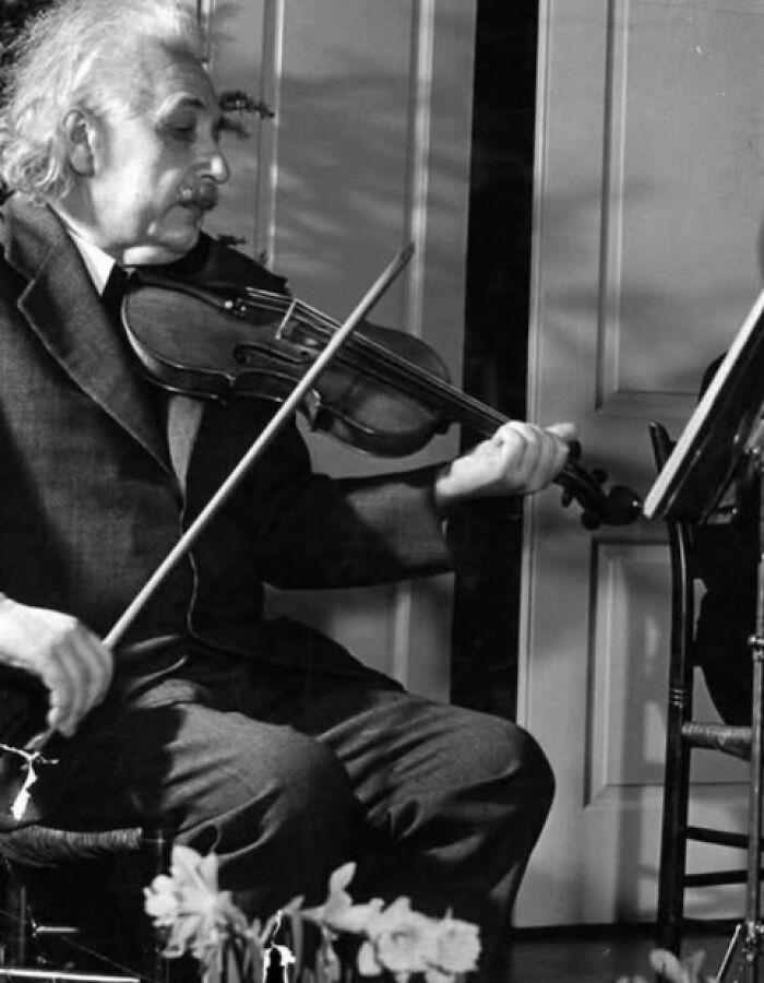 A historic black-and-white photo of a man playing the violin, showcasing timeless resonance over a hundred years.