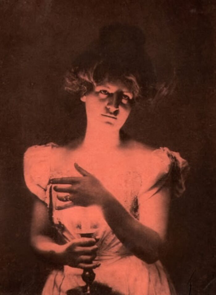 Vintage photo of a woman holding a candle, capturing historical essence from over a hundred years ago.