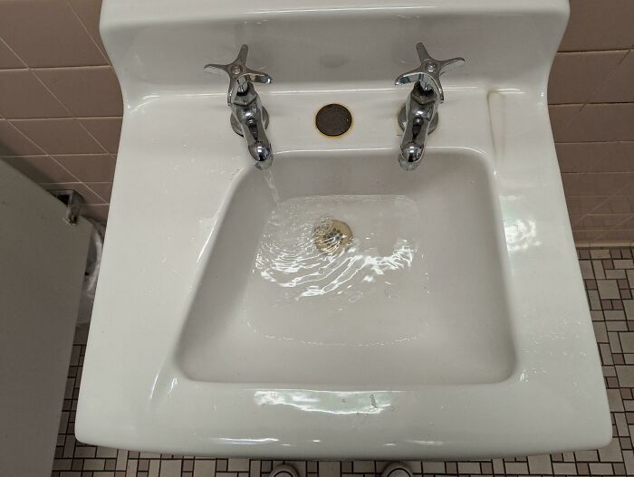 Sink design fail with misaligned faucets causing uneven water flow.