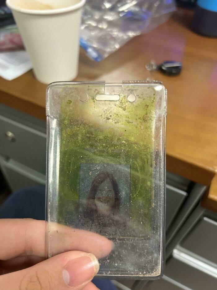 A well-worn ID holder displaying wear over time, set on an office desk with a coffee cup nearby.