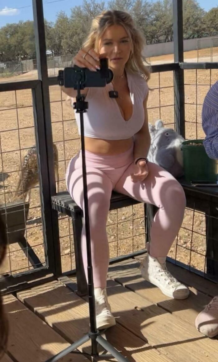 An influencer taking a selfie with a smartphone in a sunny outdoor setting.