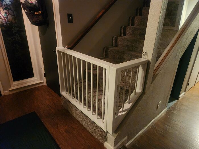 Indoor baby gate installed at the bottom of carpeted stairs, showcasing dads doing their best parenting moments with safety measures.